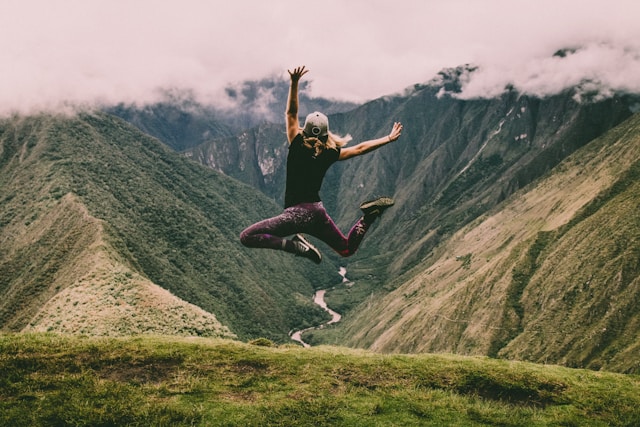 A young person leaping with joy and enthusiasm facing a vast landscape